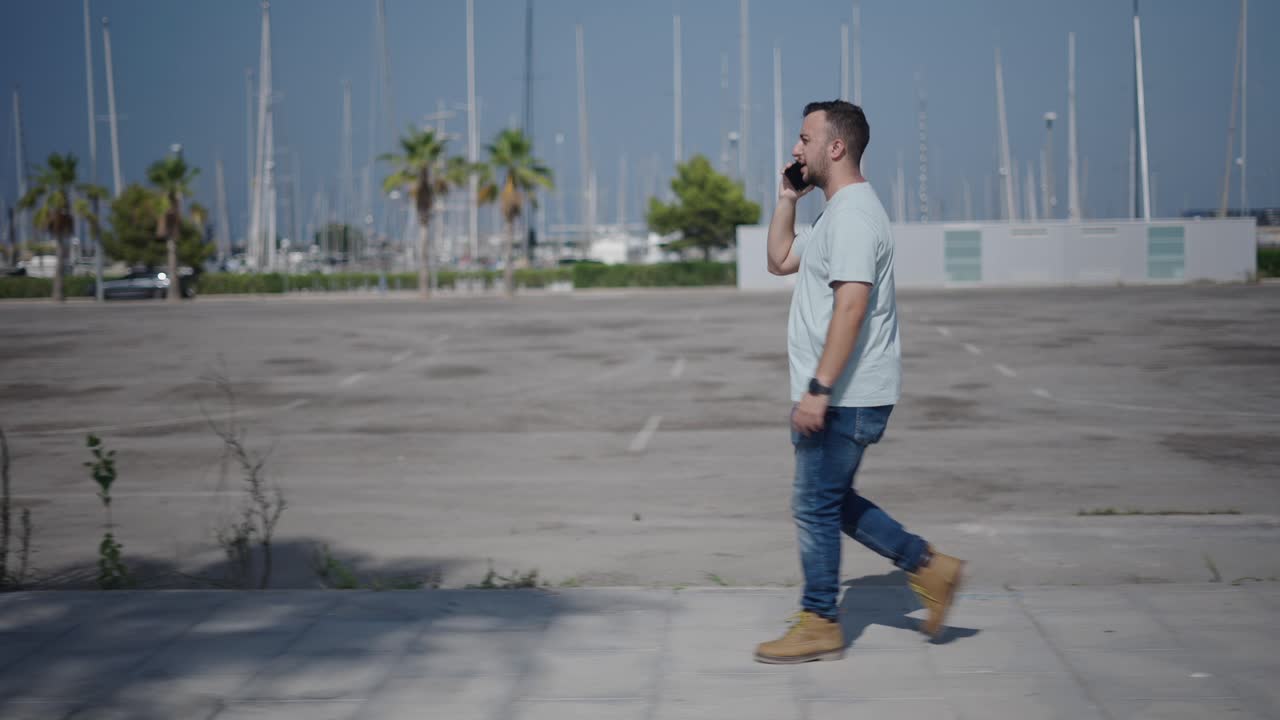 Man Walking and Talking on Phone in a City Parking Lot