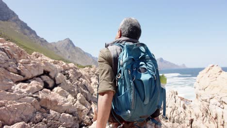 senior biracial man in mountains resting at sea, in slow motion