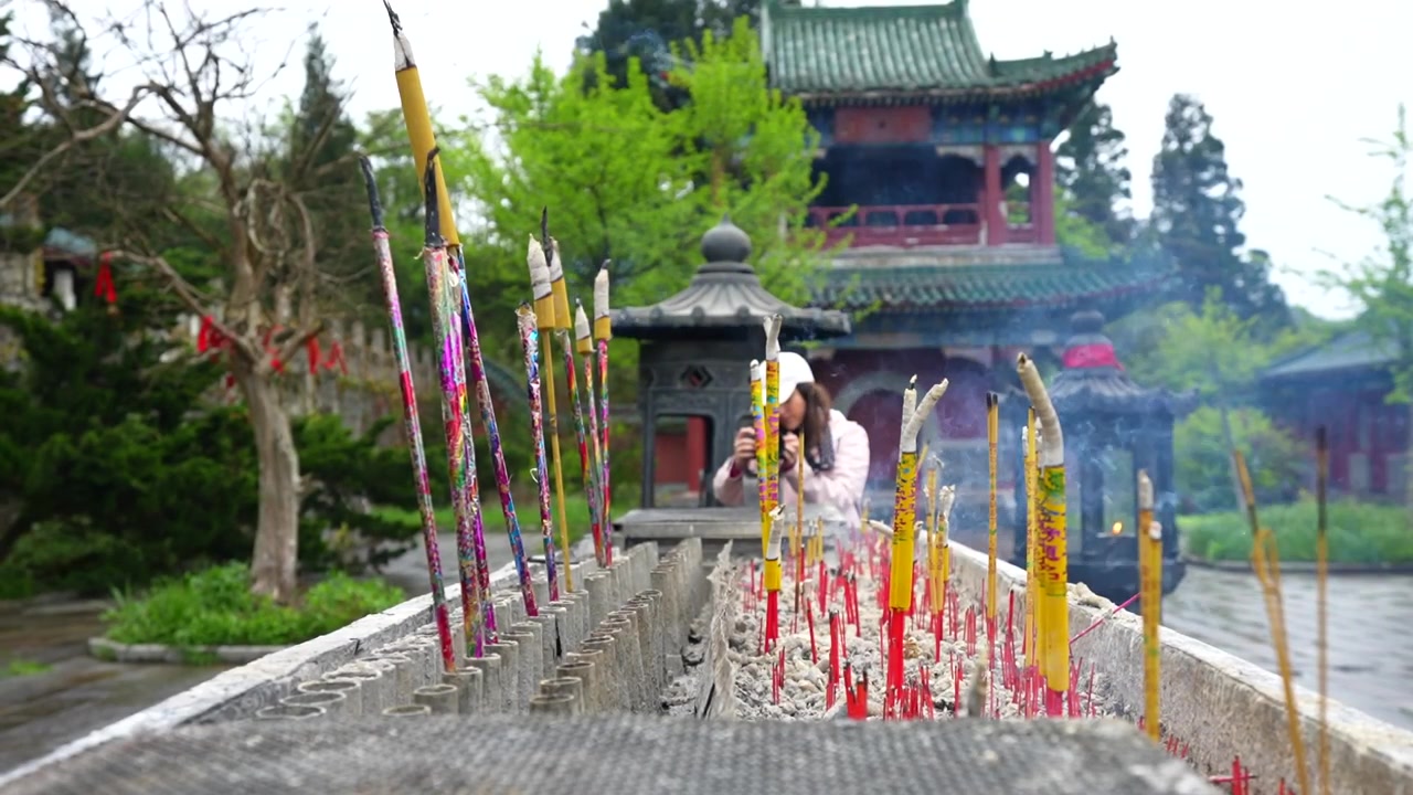 Tyk røg stiger op fra brændende røgelse ved et buddhistisk tempel i Zhangjiajie, Kina.