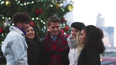 friends stand in front of christmas tree on south bank in london