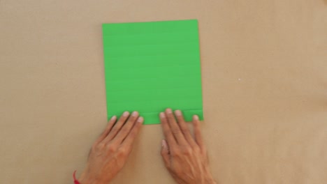 male folds green paper into traditional mexican fan