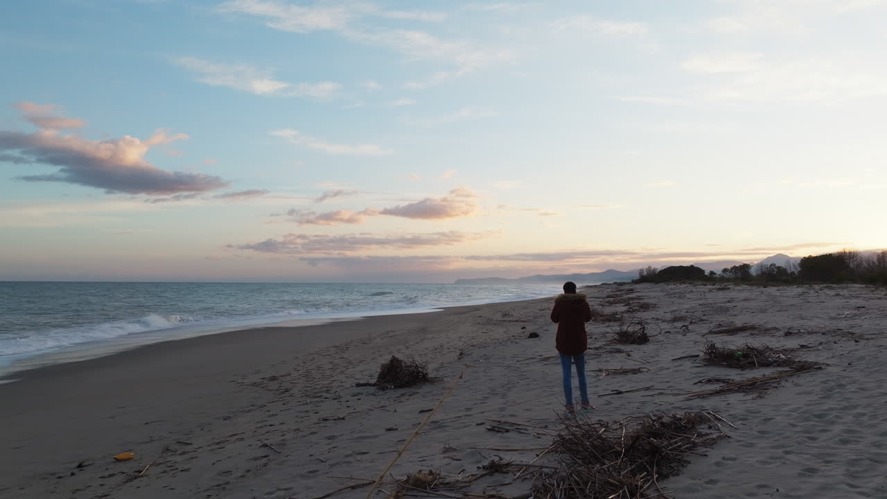 남자는 해가 지은 후 바다 근처의 파란 시간에 해변에서 사진을 찍습니다.