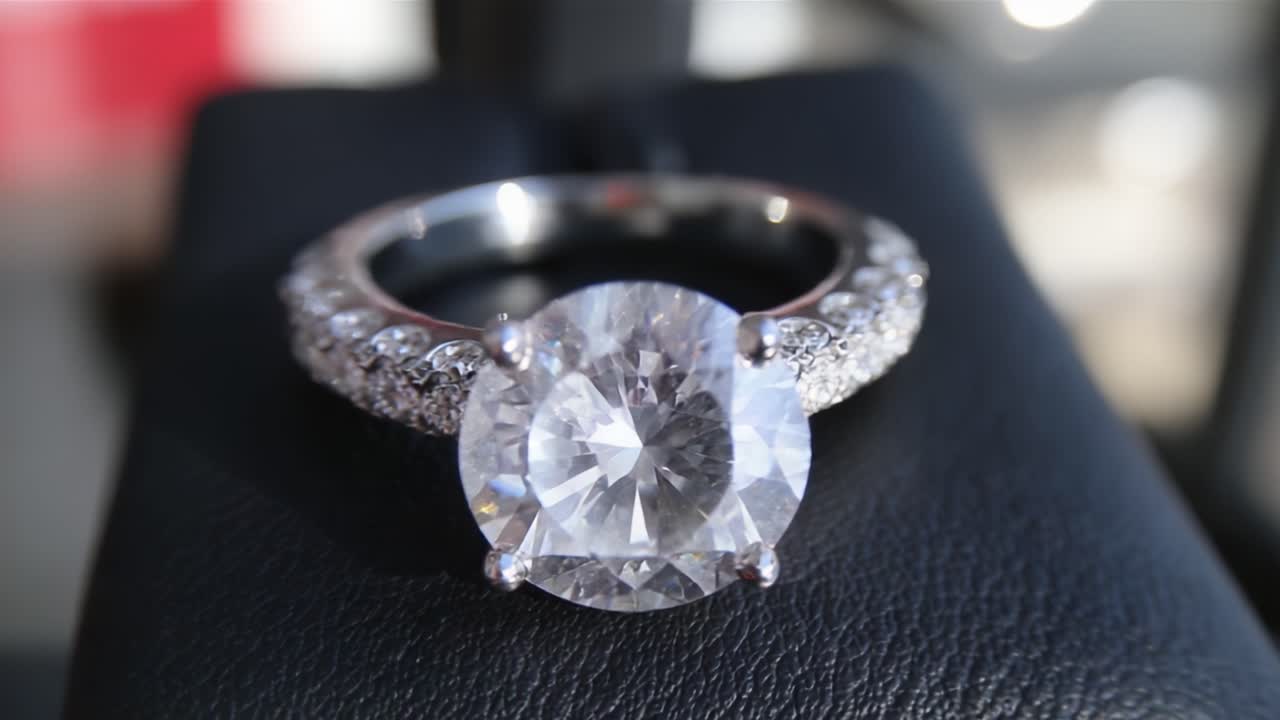 Splendido anello di fidanzamento con diamante che mostra un taglio brillante e accenti scintillanti su un lussuoso espositore di velluto nero, ideale per proposte di matrimonio e occasioni speciali.