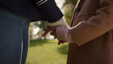 mom daughter holding hands in sunny park together closeup. happy mother child.