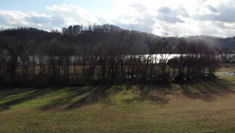 aerial footage flying up over trees with river in the background