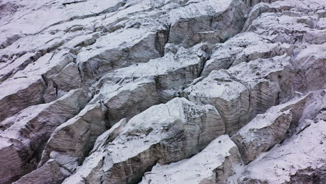 rotierende filmische drohnenaufnahme des schneebedeckten und felsigen geländes des ak-sai-gletschers in kirgisistan