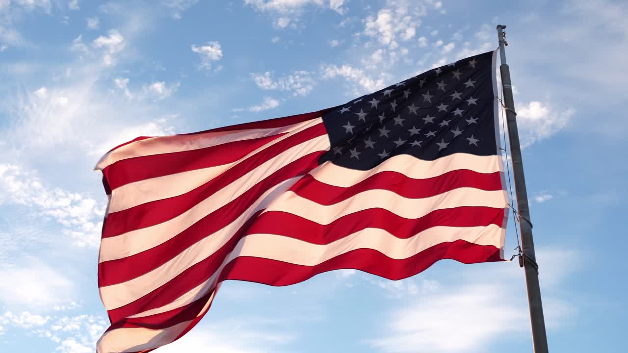 Det amerikanske flag blafrer i vinden med strålende farver. Alt dette under en smuk blålig himmel med hvide skyer.