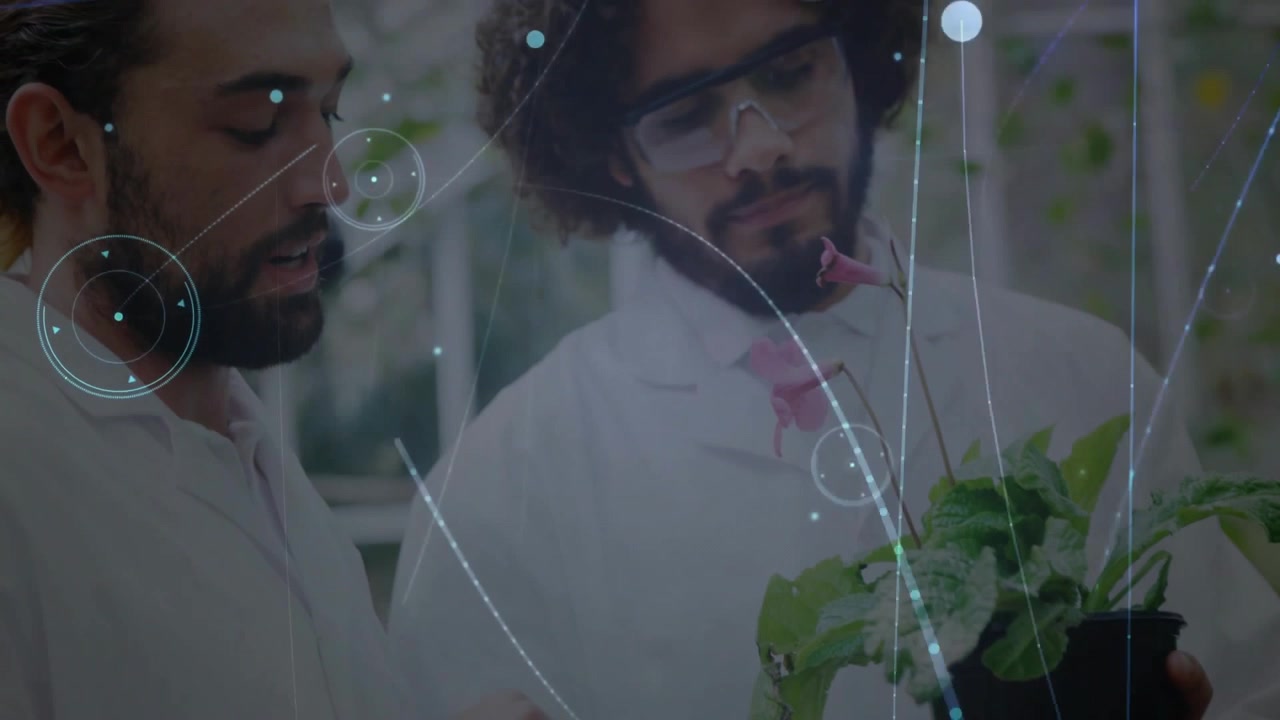 Two Scientists Examining a Potted Plant in a Greenhouse