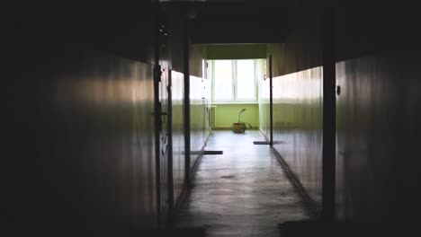 slow motion in an old dark empty corridor in a block of flats, a stylized place with a window at the end of the corridor, camera movement from ceiling to floor