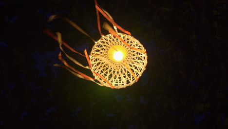 Lantern-with-paper-ribbons-moving-in-the-wind-on-dark-background,-close-up