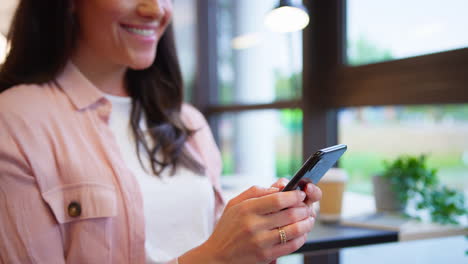 primer plano de una mujer de negocios sentada en un escritorio en la oficina enviando mensajes de texto o navegando en el teléfono móvil