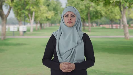 serious muslim woman looking at the camera in park