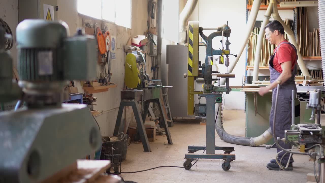 Man using a drill press in a woodworking workshop