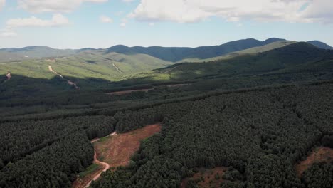 Drone-video-over-mountain-forest-dirt-roads-partially-cloudy-summer-day