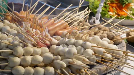 close-up footage of many kinds of steamed skewers displaying at street food market