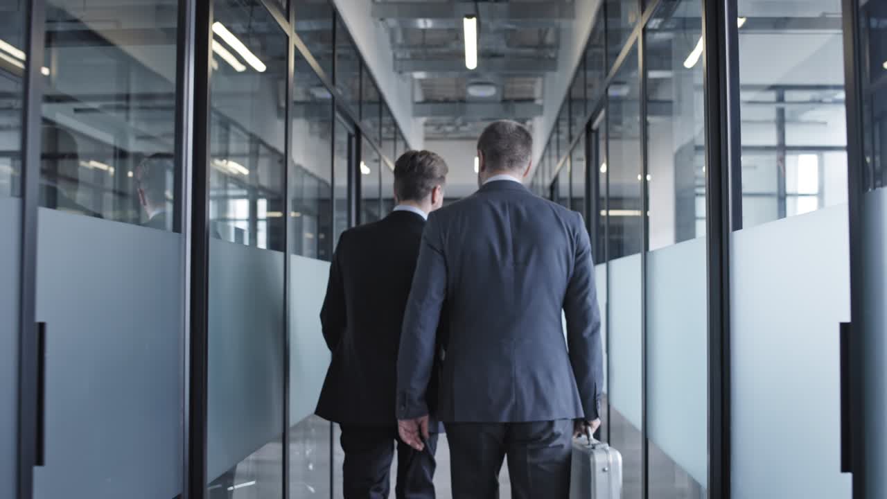 Slow motion of two male business partners walking office corridor, cooperation