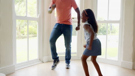 african american, father and daughter dancing joyfully at home near large windows