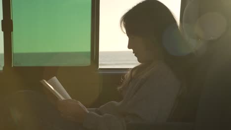 Mujer-Viajera-Leyendo-Un-Libro-En-Una-Camioneta-Al-Atardecer