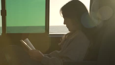 mujer viajando leyendo un libro en una furgoneta al atardecer