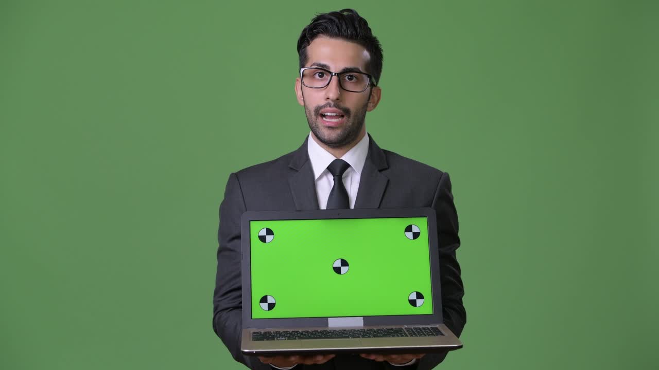 joven empresario persa barbudo y guapo contra un fondo verde