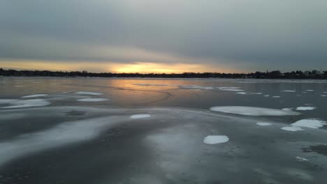 aerial view of a frozen lake with rare ice formations, sun setting on the horizon