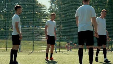 Gruppe-Junger-Fußballspieler,-Die-An-Einem-Sonnigen-Tag-Auf-Einem-Straßenfußballplatz-Trainieren-Und-Sich-Gegenseitig-Ball-Zuspielen-1