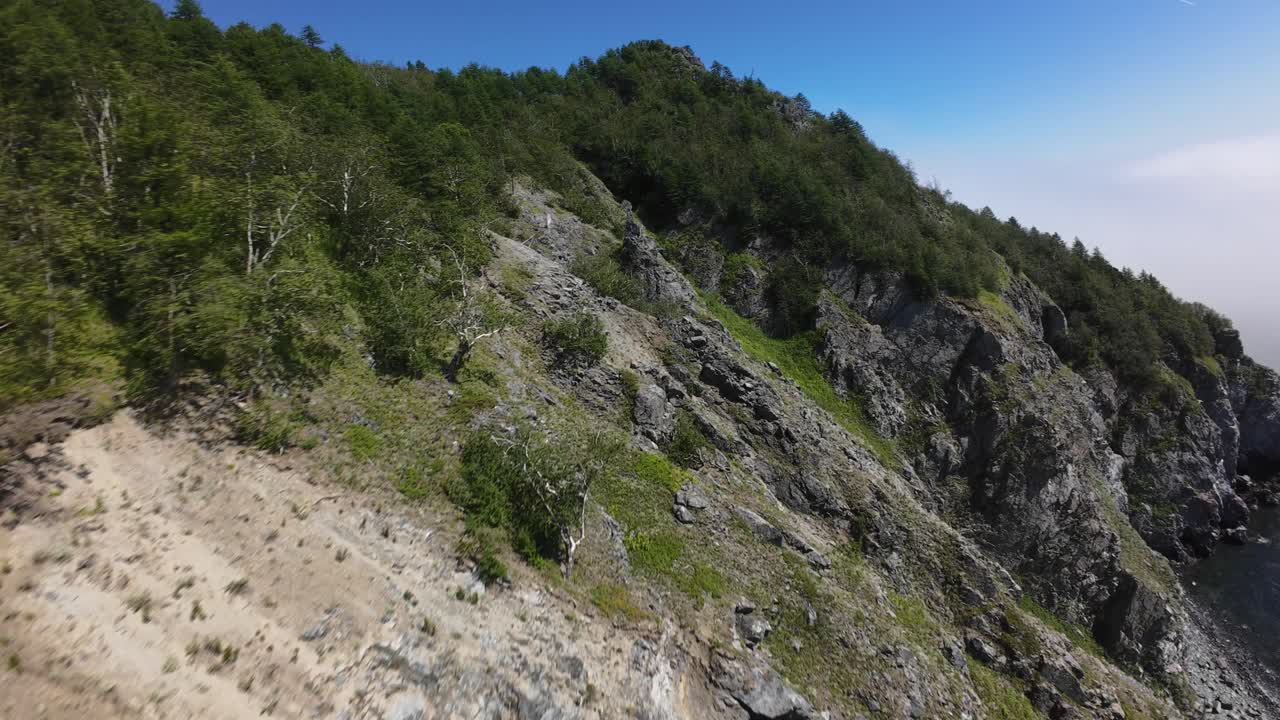 Enjoy breathtaking views of cliffs and greenery along the coastline, filmed with an FPV drone