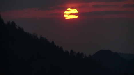 el sol se pone lentamente a través de las nubes detrás de una cresta silueteada