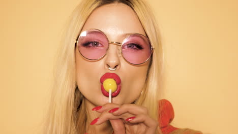 mujer con piruleta y gafas de sol rosas