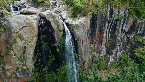 agua que fluye altos acantilados terreno vista aérea corriente de fuerza chocando rocas de musgo