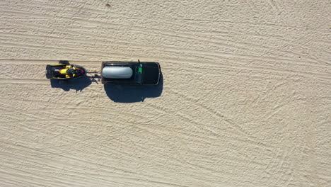 a sports utility vehicle tows a jet ski on the beach