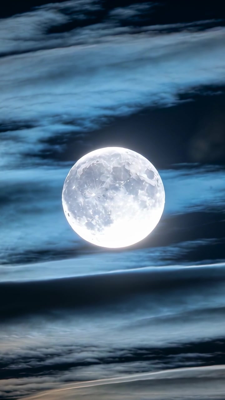 縦型動画：夜空を横切って薄い雲を動かす風の中、ズームで大きく映し出される漂う満月。