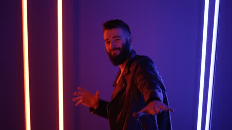 close up view of young man dancing looking at camera on purple neon lights background