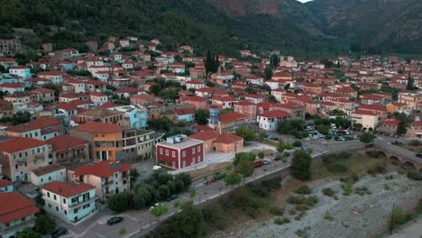 dry riverbed and iconic red orange roofed homes vibrant colors in leonidio, greece, aerial