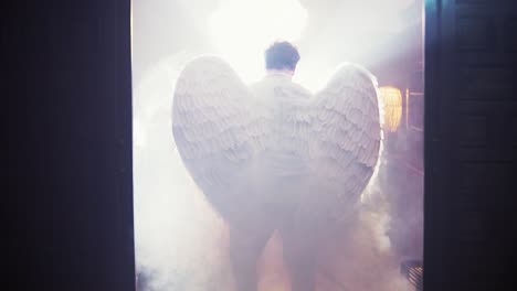 cinematic rising shot of a man wearing angel wings rising through the smoke cloud