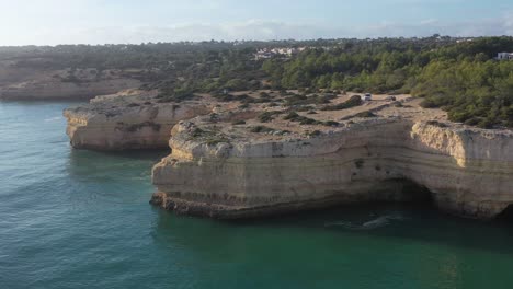 Fontainhas-Beach-in-Portugal-with-camping-van-parked-on-top-of-eroded-sea-cave-area,-Aerial-circle-reveal-shot