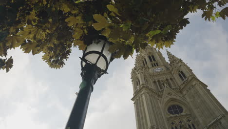 light pole, tree leaves and majestic church tower with clock in san sebastian, motion view