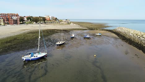 aerial view boats in shimmering low tide sunny warm rhos on sea sandy seaside beach marina resort slow orbit right