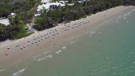 sombrillas de playa en la orilla de la playa de cuatro millas en port douglas, australia - toma aérea de drones