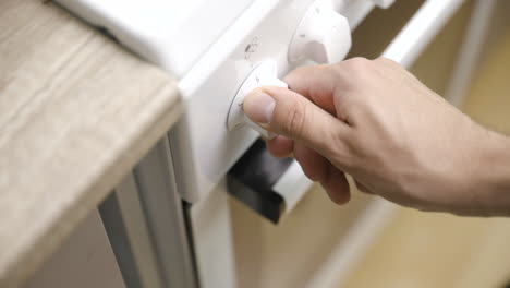 Close-view-from-above-of-hand-turning-on-and-off-stove-on-white-knob