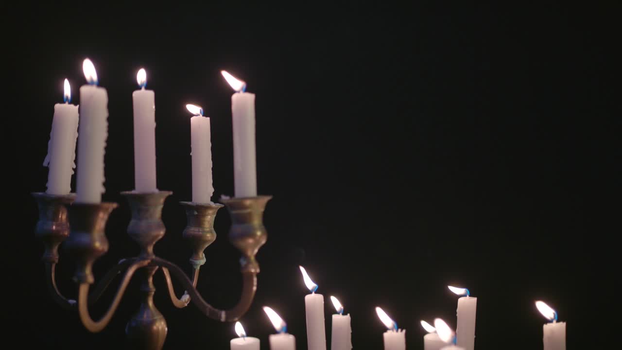 un grupo de velas blancas, algunas en un candelabro iluminadas y luego apagadas por el viento