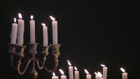 a group of white candles some on a candelabra lit up then blown out by the wind