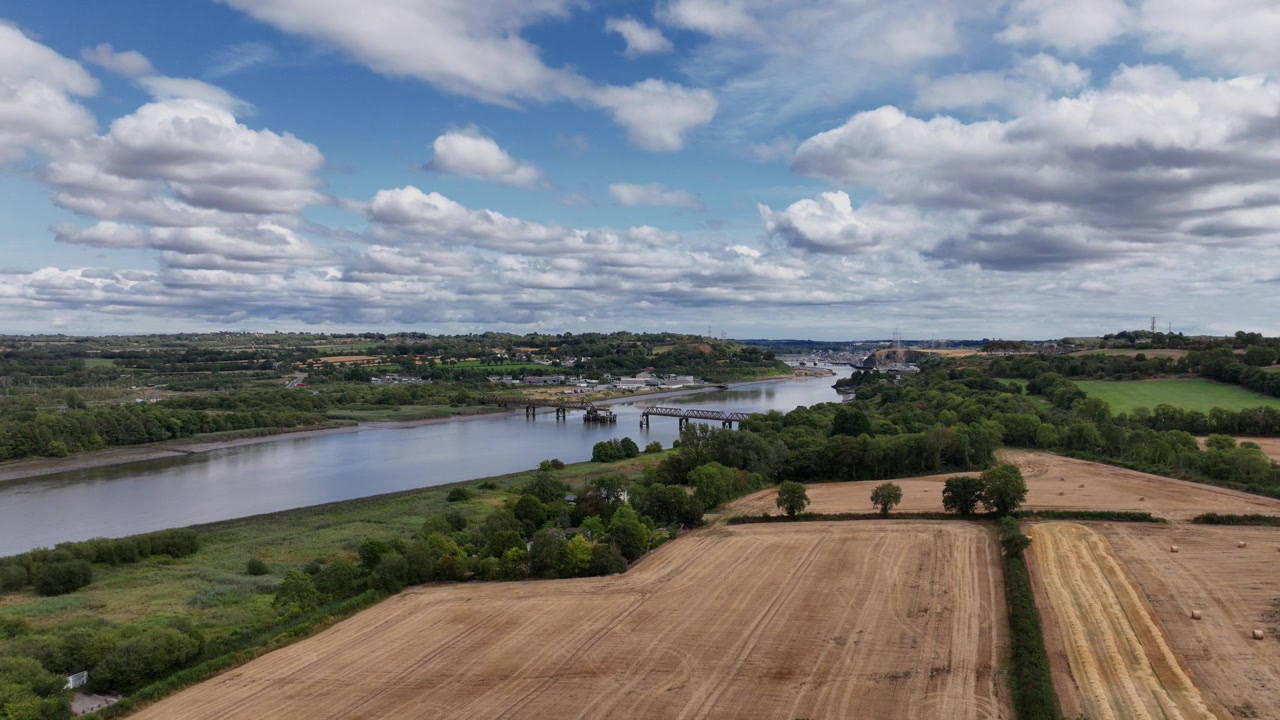 Impresionante vista aérea de las fértiles tierras de cultivo de Irlanda a orillas del río Suir, con los suburbios de la ciudad de Waterford al fondo durante el verano