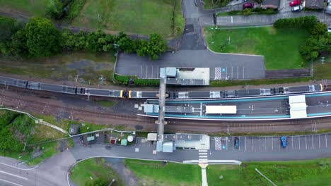 Toma-De-Paisaje-Aéreo-De-Drones-Del-Tren-De-La-Ciudad-En-La-Plataforma-De-La-Línea-Ferroviaria-Parque-Niágara-Lisarow-Estación-Ourimbah-Transporte-De-La-Costa-Central-Australia-4k