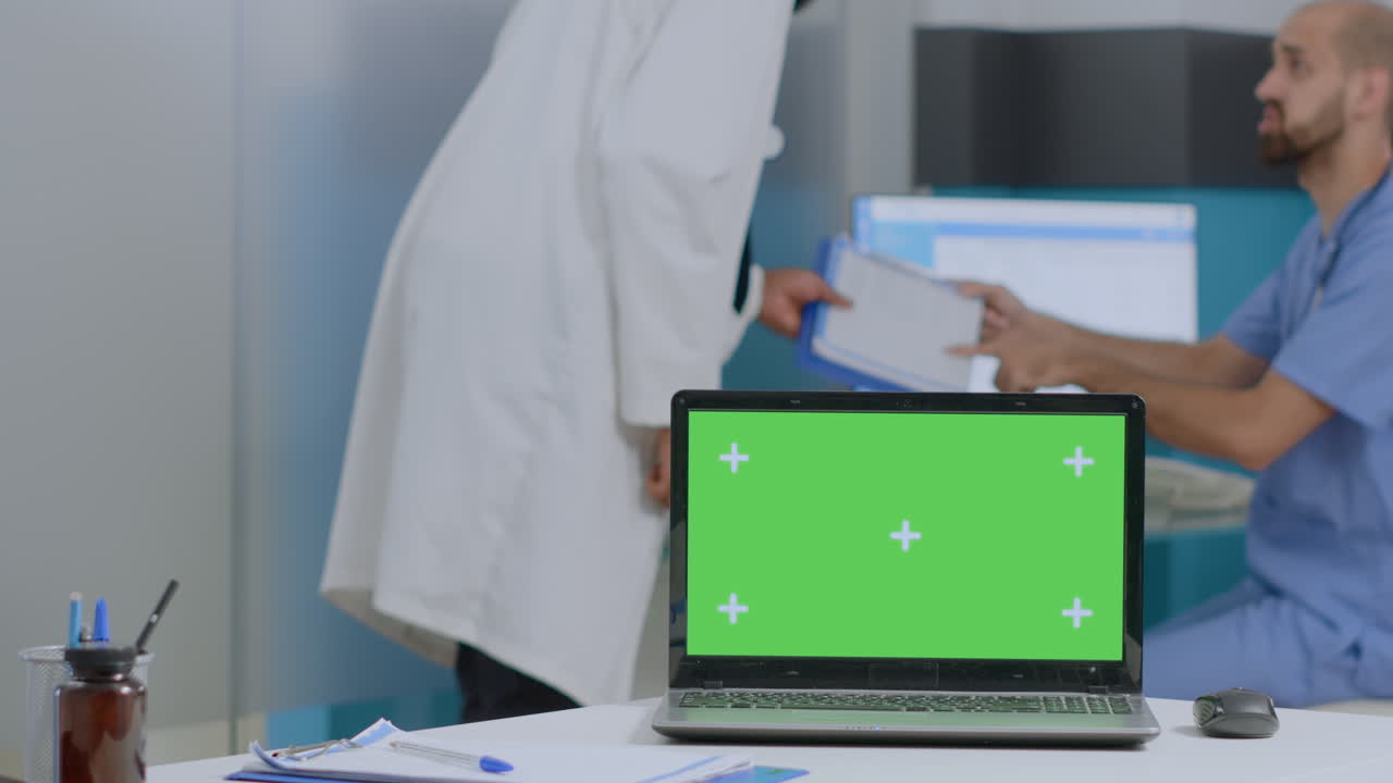 Medical professionals using laptop with green screen in clinic