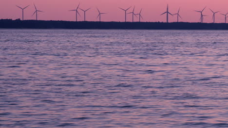 rotating wind turbines at pink sunset