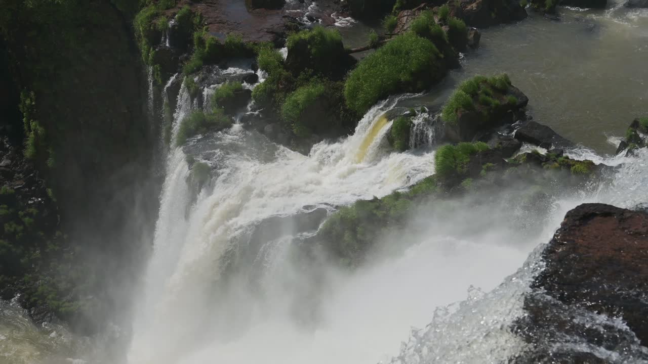 increíble agua clara derramando, cayendo profundamente en la selva tropical argentina, mucha naturaleza cubierta de áspera hermosa corriente de cascada corriendo por un acantilado rocoso en las cataratas de iguacu, américa del sur