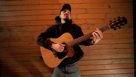 man plays the guitar and sings songs in a tent with light bulbs