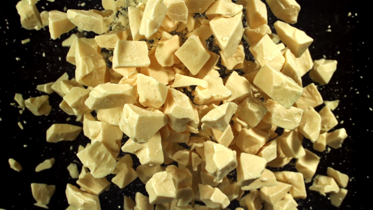 White Chocolate Chunks Falling on Black Background in Slow Motion