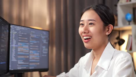 close up of asian woman programmer smiling and crossing his arms while creating software engineer developing app, program, video game on desktop computer at home